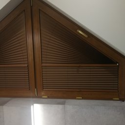 F.H.U. Artur Grabarczyk - Brązowe plisy zamontowane w oknie o nietypowym, trójkątnym kształcie, drewniana rama okienna, widok z dołu.