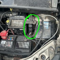 Mobilny Mechanik Elektryk Samochodowy Gdańsk Gdynia Sopot - Widok z góry na brudny silnik samochodu z widocznym akumulatorem i filtrem powietrza, z zaznaczonym na zielono obszarem potencjalnej usterki.