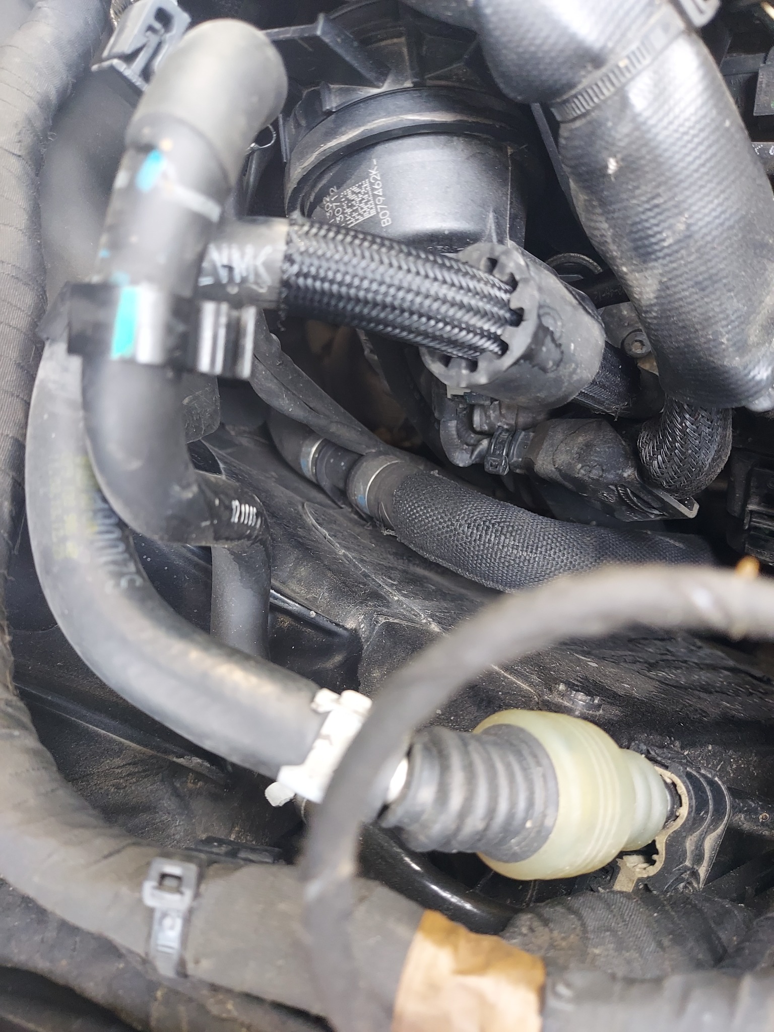 Szczegółowe ujęcie wnętrza komory silnika samochodu z widocznymi przewodami, złączkami i elementami osprzętu, ukazujące skomplikowaną sieć połączeń w pojeździe.