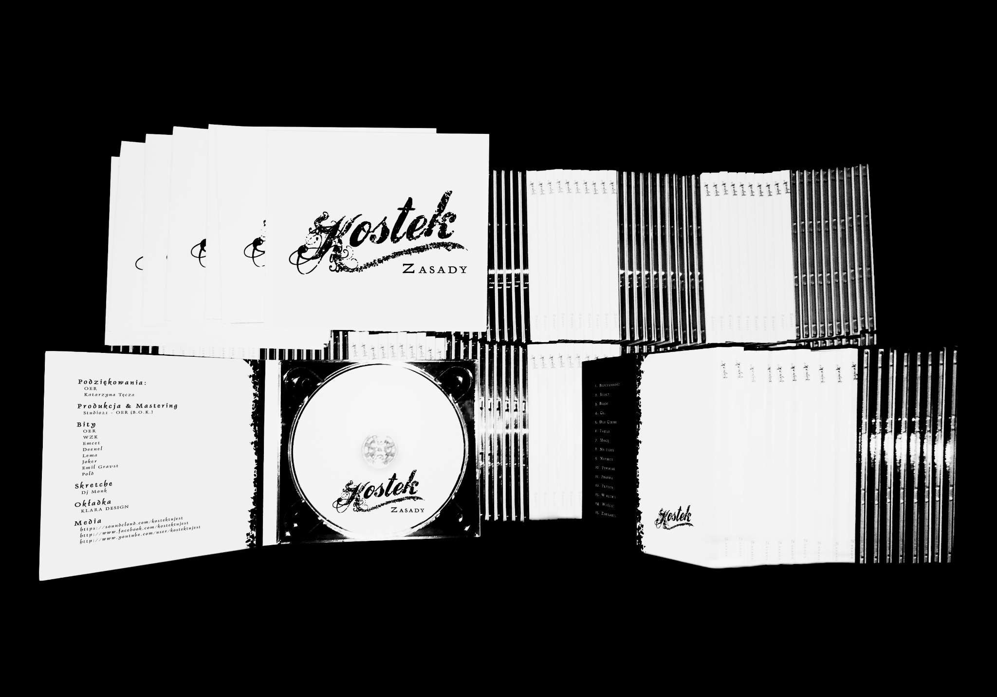 Stos płyt CD z okładkami albumu 'Kostek - Zasady', prezentacja projektu graficznego opakowania, widoczne detale typografii i logo.