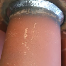 MICHAŁ GĄSIOROWSKI „SDC” - Specjalista dla Ciebie - Spoina spawalnicza łącząca rurę z kołnierzem, widoczne ślady po spawaniu na pomarańczowej powierzchni.