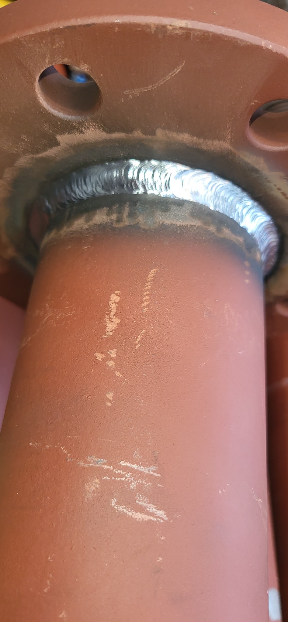 Spoina spawalnicza łącząca rurę z kołnierzem, widoczne ślady po spawaniu na pomarańczowej powierzchni.