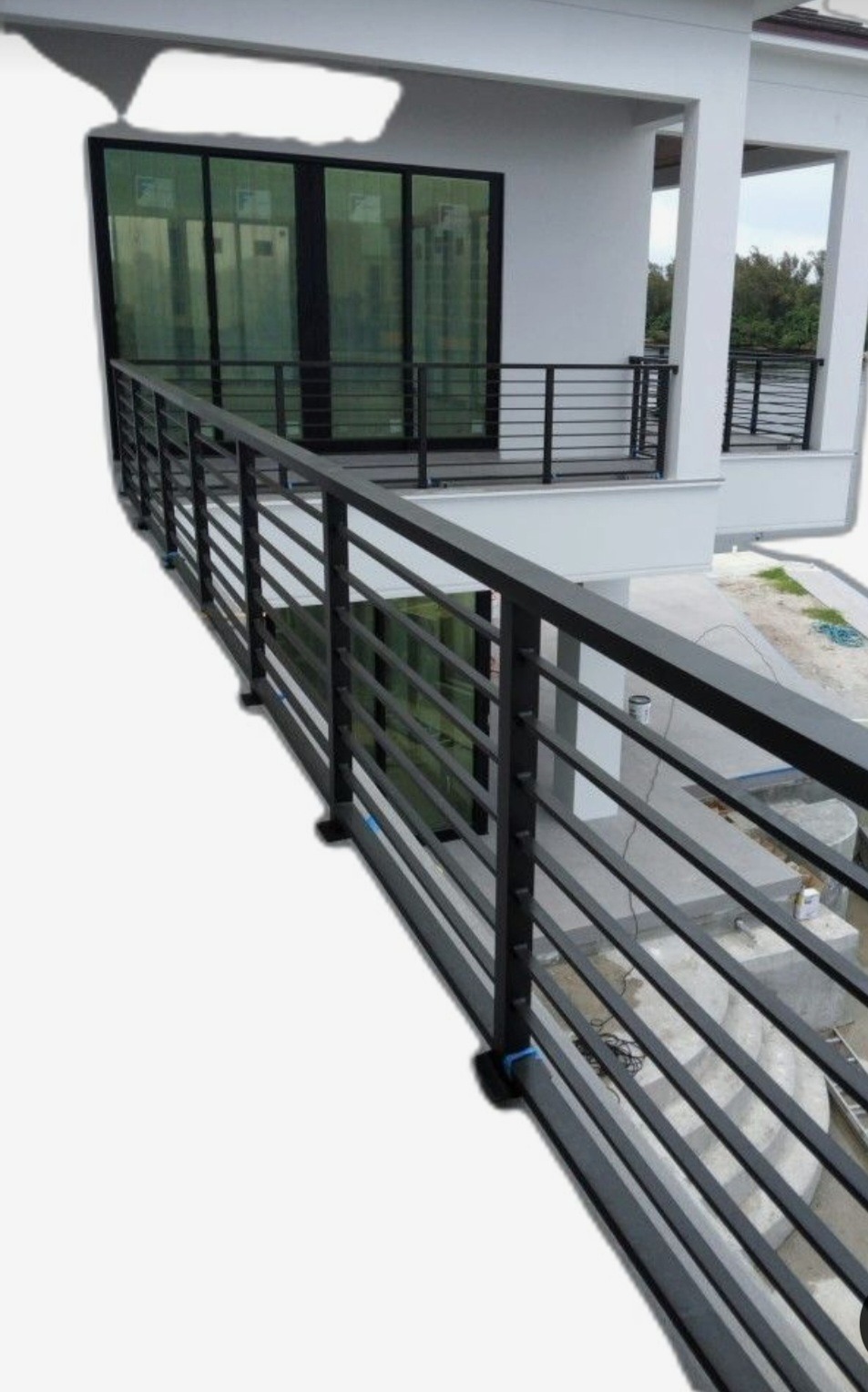 Nowoczesna, czarna balustrada metalowa z poziomymi szczeblami na balkonie budynku w stylu minimalistycznym, widok z dołu pod kątem.