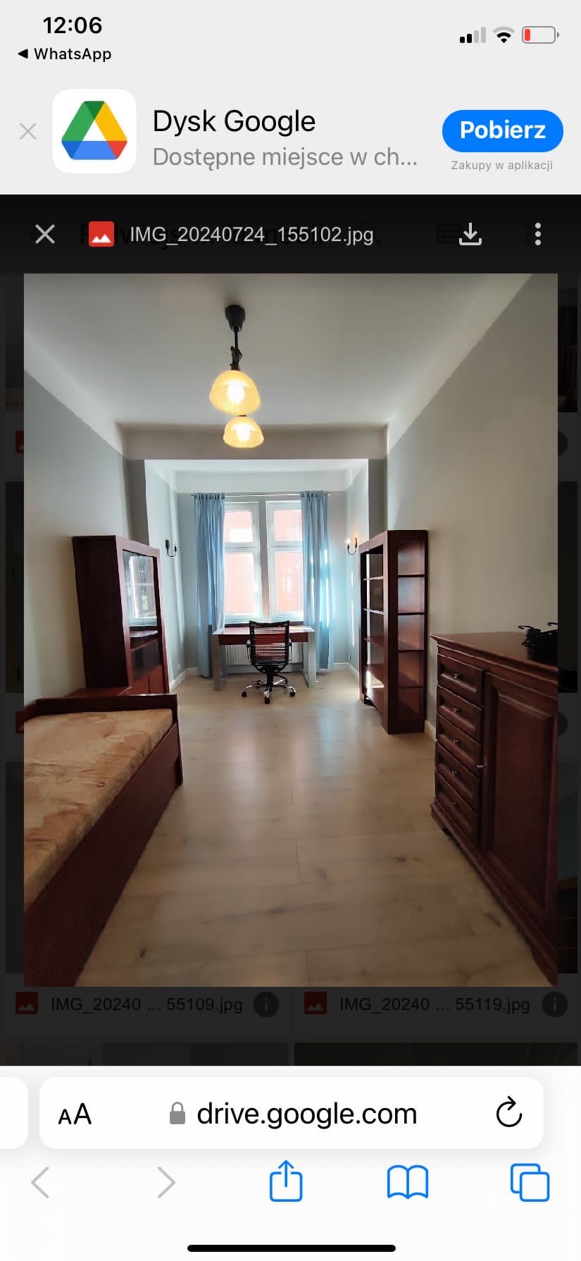 Jasne wnętrze pokoju po remoncie z drewnianą podłogą, biurkiem pod oknem z niebieskimi zasłonami, drewnianymi meblami i lampą sufitową.