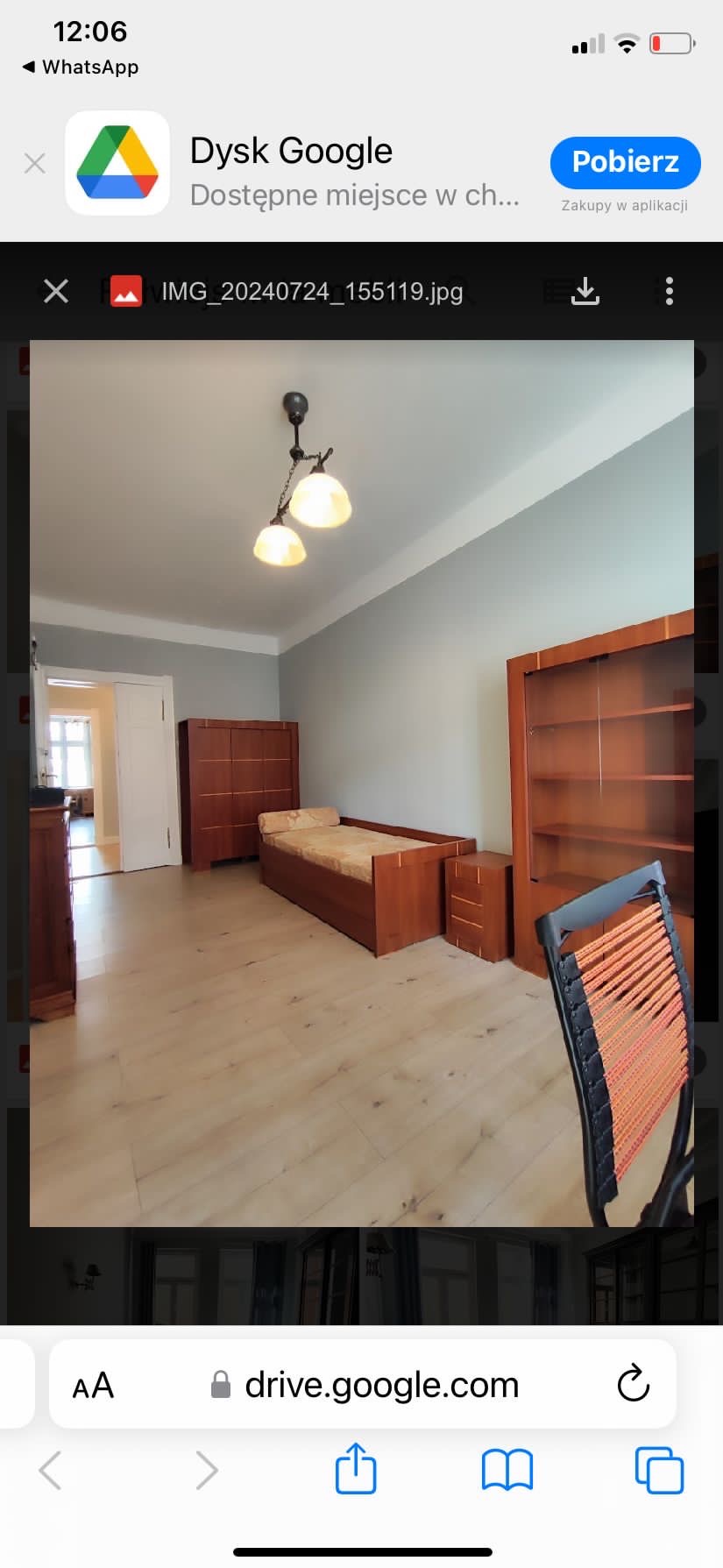 Jasne, świeżo odmalowane wnętrze pokoju z drewnianymi meblami: łóżkiem, szafą i regałem, podłoga z paneli, widok na kolejne pomieszczenie przez otwarte drzwi.