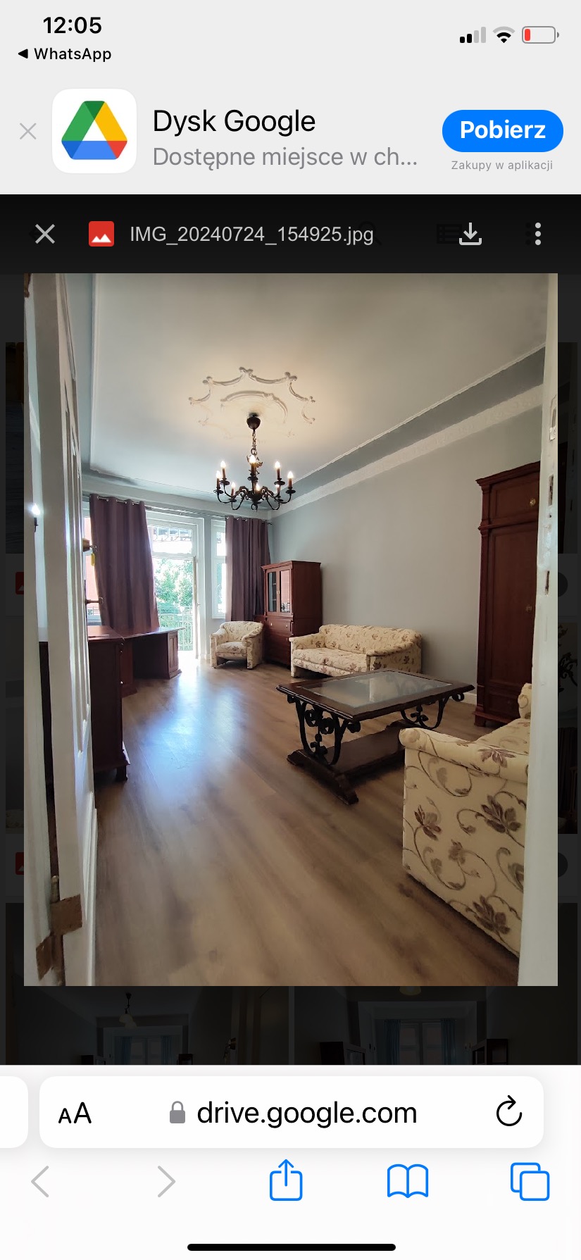 Salon po remoncie z drewnianą podłogą, szarą ścianą, brązowymi meblami i żyrandolem w stylu retro