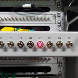 POKABLOWANI.NET SPÓŁKA Z OGRANICZONĄ ODPOWIEDZIALNOŚCIĄ - Panel krosowniczy z portami oznaczonymi numerami, z których jeden świeci na czerwono, widoczne kable i elementy szafy rack.