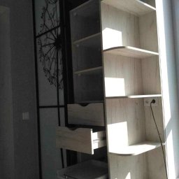 Gl meble meble na wymiar - Jasna szafa z przesuwnymi drzwiami z motywem dmuchawca, widoczne otwarte szuflady i półki, oświetlone promieniami słonecznymi