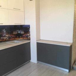 Gl meble meble na wymiar - Fragment nowoczesnej kuchni z szarymi szafkami dolnymi, jasnym blatem i fototapetą z nocnym widokiem miasta nad zlewem.