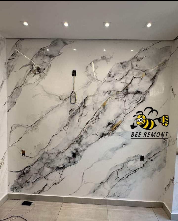 Ściana z dekoracyjnym malowaniem imitującym marmur, widoczne gniazdka elektryczne i logo firmy 'BEE REMONT'