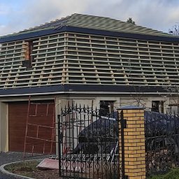 Gedbud Grzegorz Ged - Konstrukcja więźby dachowej z łatami na domu jednorodzinnym, widok z poziomu chodnika, brama w tle.