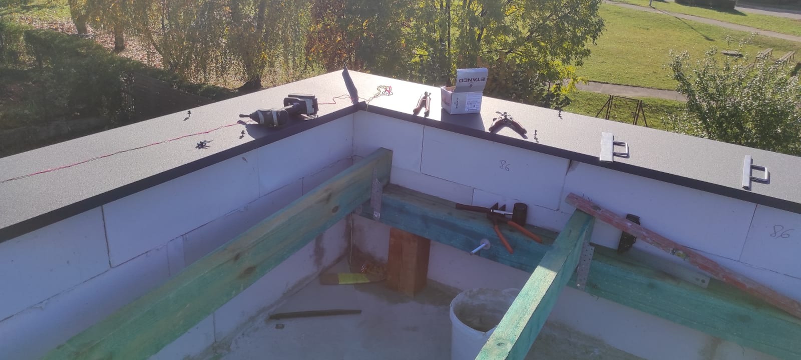 Montaż izolacji termicznej dachu płaskiego z użyciem bloczków z betonu komórkowego, narzędzi dekarskich i akcesoriów ETANCO.