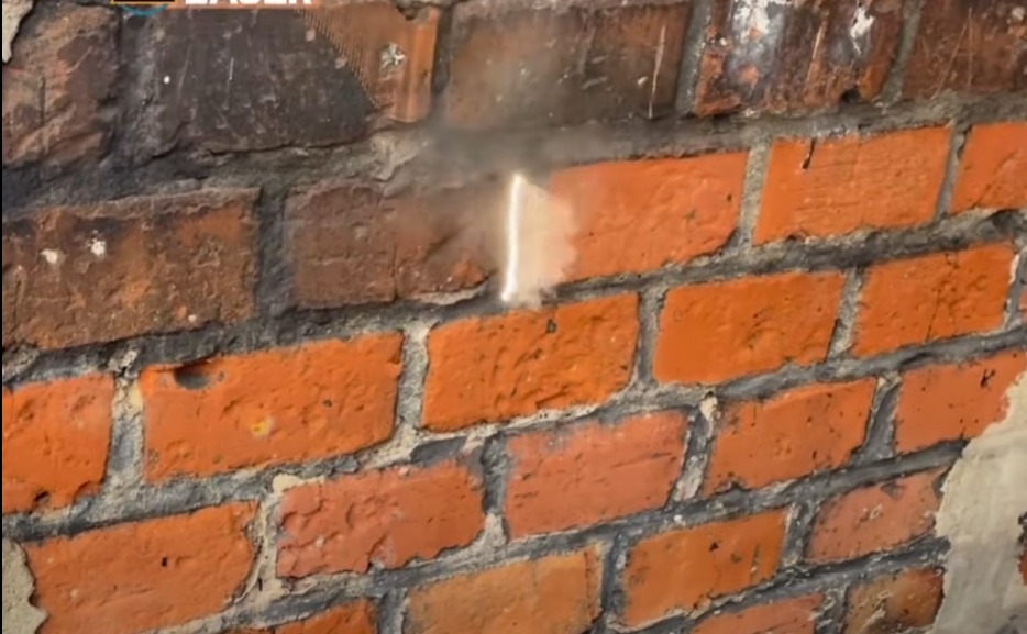 Czyszczenie ceglanej ściany strumieniem piasku, widoczny efekt oczyszczenia fragmentu powierzchni.