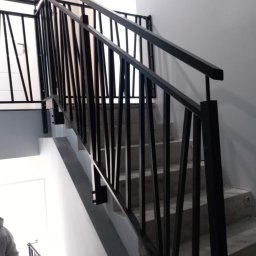 Stal Zachodniopomorskie - Nowoczesne czarne poręcze schodowe z pionowymi prętami na betonowych schodach wewnątrz budynku, widok z dołu.