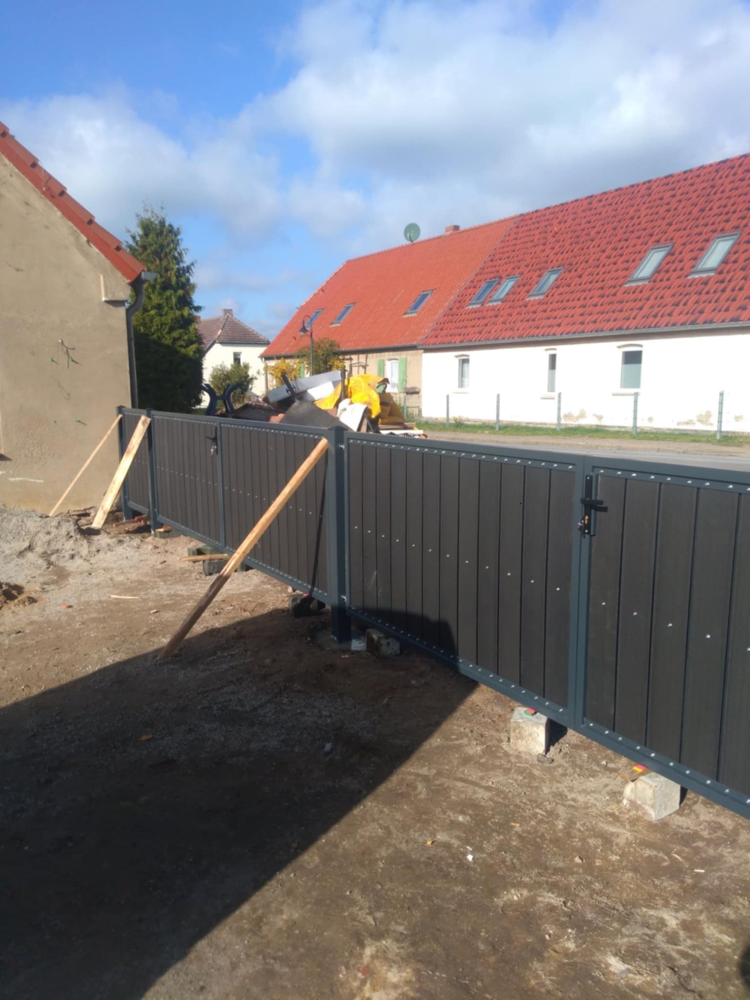 Montaż nowoczesnego ogrodzenia panelowego z bramą wjazdową w Szczecinie, widoczne drewniane podpory stabilizujące konstrukcję podczas instalacji.