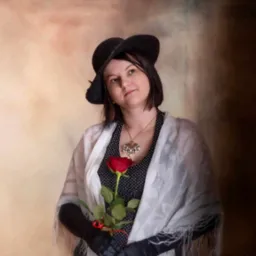Portret kobiety w kapeluszu i rękawiczkach trzymającej czerwoną różę na tle malowanego tła, stylizowany na retro, wykonany przez fotografa z Rzeszowa.
