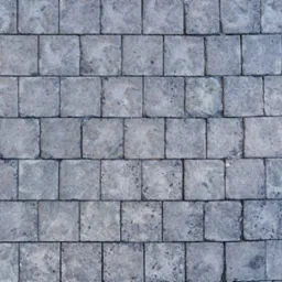 Szara kostka brukowa ułożona w prosty wzór, widoczne szczeliny między kostkami wypełnione drobnym piaskiem.