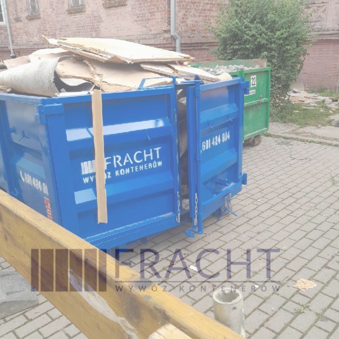 Niebieski kontener na gruz wypełniony odpadami budowlanymi, z otwartymi drzwiami, na tle brukowanej nawierzchni i zielonego kontenera w tle.