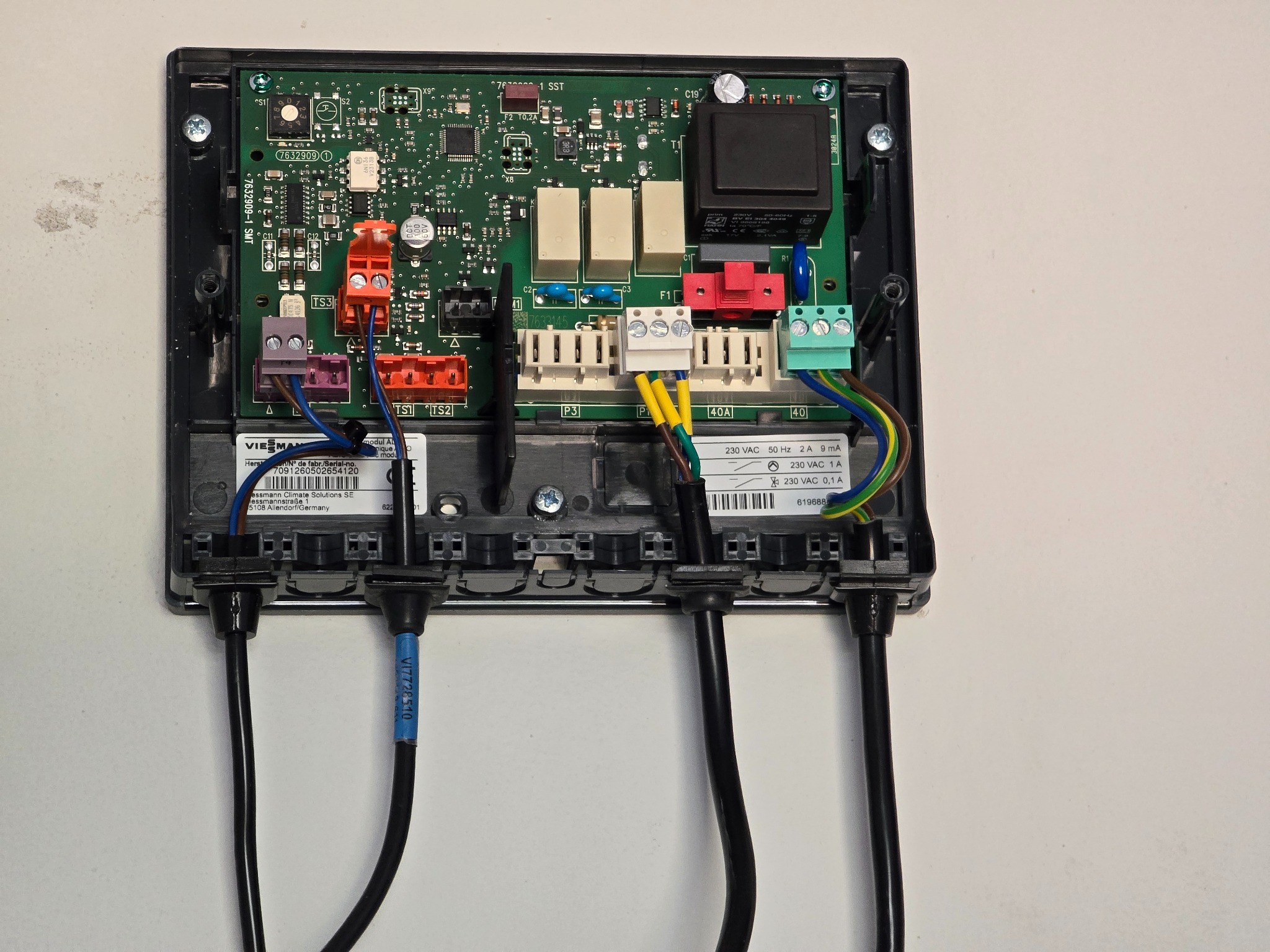 Otwarta skrzynka sterownicza Viessmann z widocznymi elementami elektronicznymi, przewodami i złączami. Widoczne oznaczenia i etykiety na przewodach.