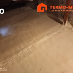 Termo-metr Tomasz Kudła - Zdjęcie przedstawia poddasze po natrysku pianki izolacyjnej, widoczne drewniane elementy konstrukcyjne i logo firmy wykonującej izolację w prawym górnym rogu. Na zdjęciu widoczny napis 'Po'...