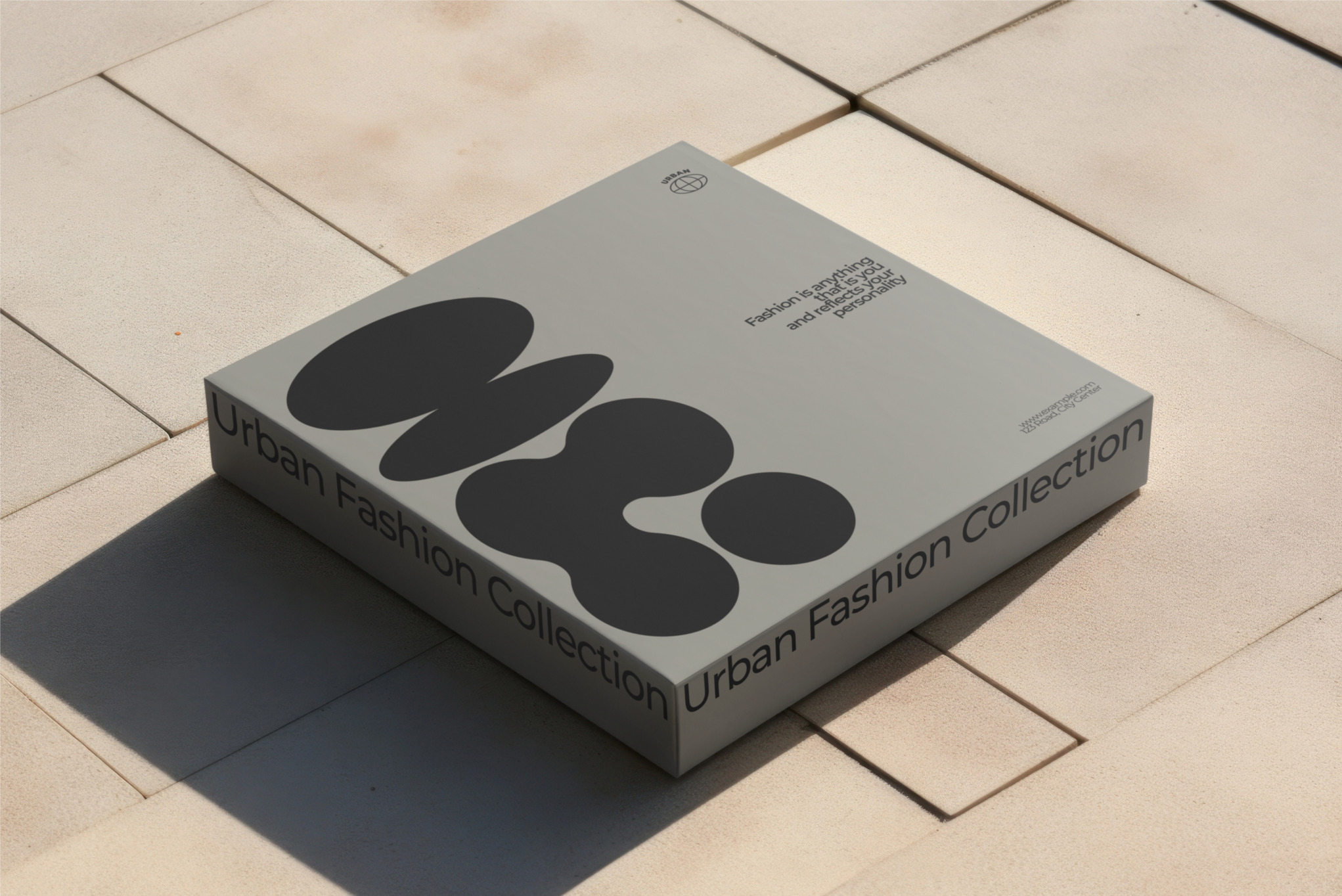 Szare pudełko z napisem 'Urban Fashion Collection' i abstrakcyjnym wzorem na beżowym tle z kwadratowych płytek.