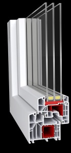 Przekrój poprzeczny białego okna z tworzywa sztucznego z trzema szybami, ukazujący wewnętrzną strukturę i komory, z czerwonymi elementami uszczelniającymi, na czarnym tle.