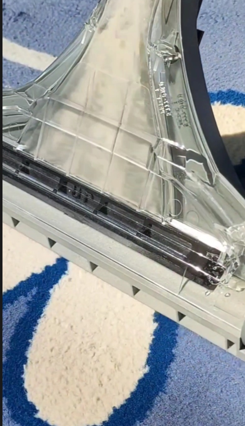 Dysza odkurzacza piorącego na wzorzystym dywanie z bliska, widoczne detale konstrukcyjne i oznaczenia na plastiku.