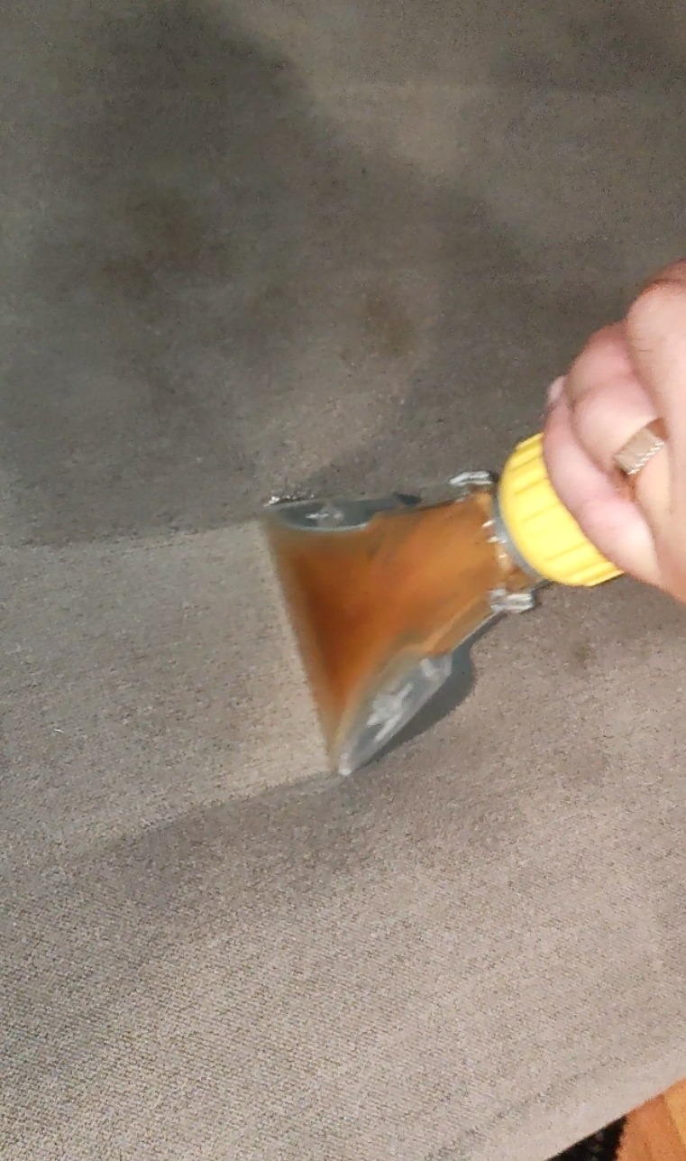 Czyszczenie jasnobeżowej sofy za pomocą ekstraktora z żółtą końcówką; widoczna brudna woda w dyszy.