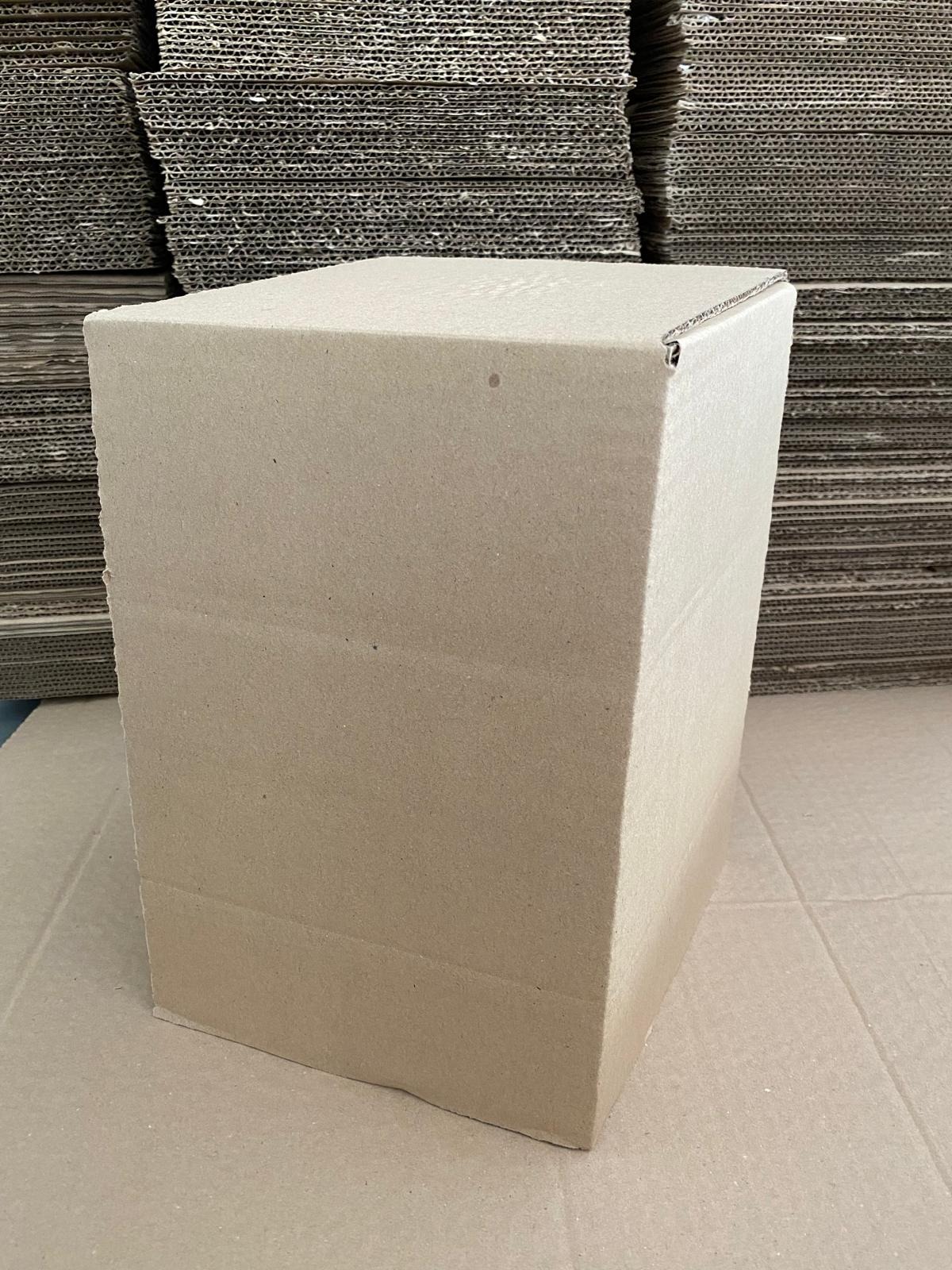 Kartonowe pudełko z tektury falistej na tle stosu arkuszy tektury w Polanowicach.