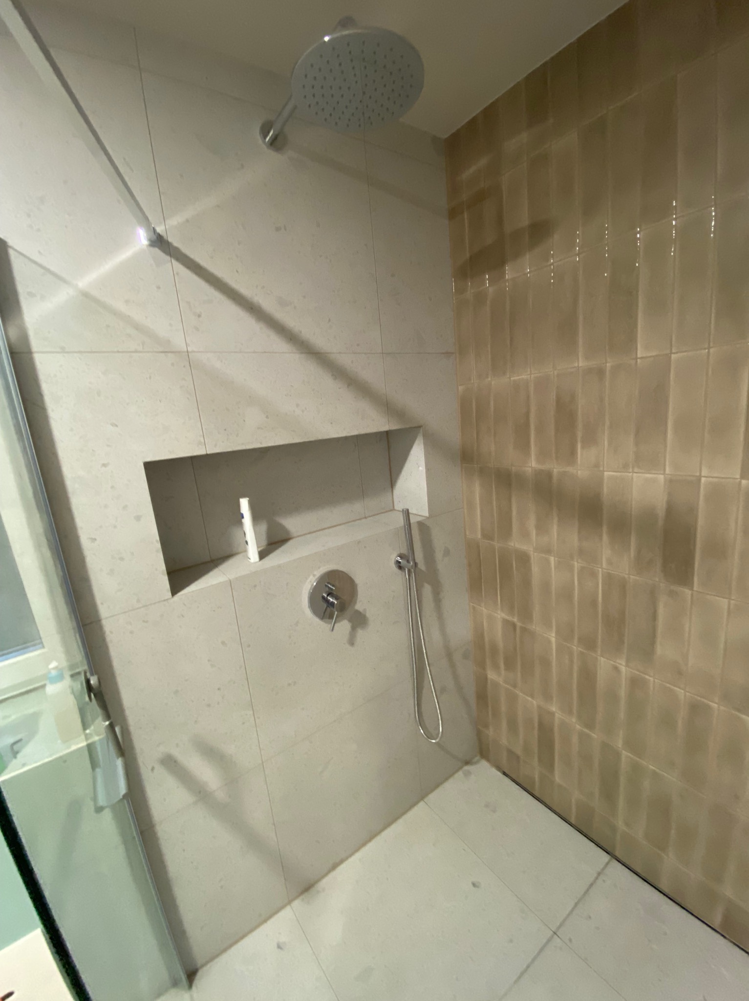 Nowoczesna kabina prysznicowa z wnęką na kosmetyki, wykończona płytkami w dwóch odcieniach, prezentowana w Dziemianach.