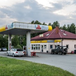 ARCAB Investments Sp. z o.o. - Stacja paliw z podjazdem, dystrybutorami, budynkiem z napisem 'KASA', 'BIURO' i 'MOTEL BAR', zaparkowanymi samochodami osobowymi i terenowym.