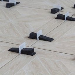 Complexx - Ułożone płytki podłogowe w jodełkę z systemem poziomowania płytek, jasne spoiny, widok z góry, oświetlenie naturalne.