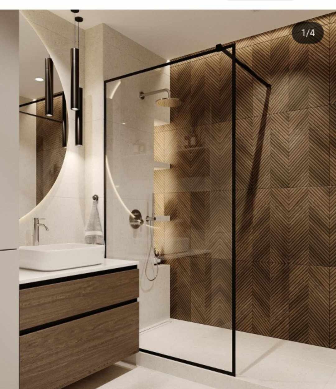 Nowoczesna łazienka z kabiną prysznicową typu walk-in z czarnymi profilami, umywalką nablatową na szafce z drewnianym frontem i dekoracyjną ścianą z płytek w geometryczny wzór jodełki.