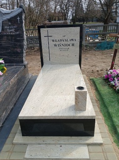 Jasny nagrobek z czarnymi elementami, z wygrawerowanym krzyżem i napisem 'Władysława Wiśnioch', ustawiony na cmentarzu, widok z przodu.