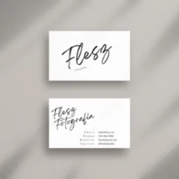 Dwie wizytówki firmy fotograficznej 'Flesz' z kaligraficznym logo na białym tle, oświetlone naturalnym światłem z cieniem rzucanym z góry.