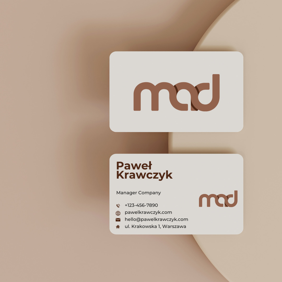 Dwie wizytówki z minimalistycznym logo 'mad' w kolorze brązowym, umieszczone na beżowym tle z subtelnym cieniowaniem.