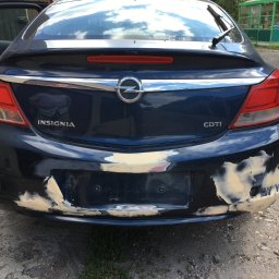 Tadeusz Nr - Niebieska Opel Insignia z uszkodzonym, szpachlowanym tylnym zderzakiem przygotowywanym do lakierowania.