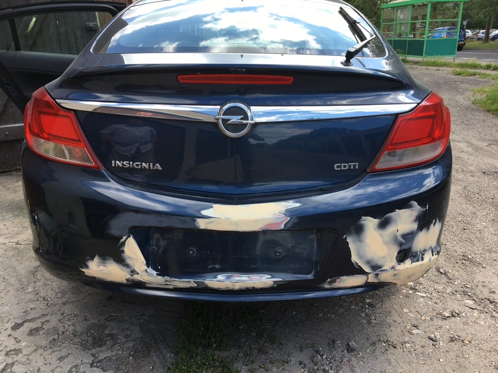 Niebieska Opel Insignia z uszkodzonym, szpachlowanym tylnym zderzakiem przygotowywanym do lakierowania.