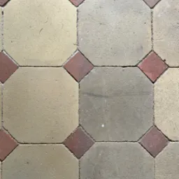 Ułożona kostka brukowa w geometryczny wzór: beżowe ośmiokąty i czerwone kwadraty. Widoczne fugi i tekstura materiału. Kąt ujęcia z góry.