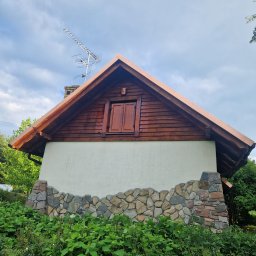 Piotr kowalski - Dom z drewnianą elewacją szczytową, oknem na poddaszu i miedzianymi obróbkami blacharskimi dachu, na fundamencie z kamienia polnego.