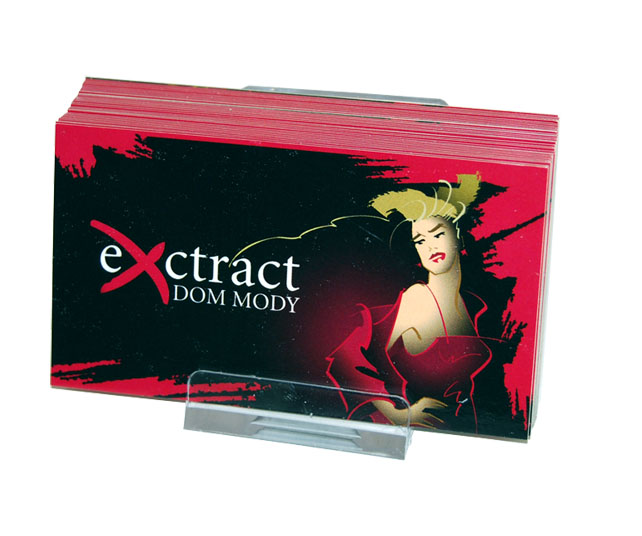 Stos wizytówek w przezroczystym plastikowym stojaku, z grafiką przedstawiającą kobietę w czerwonej sukni i logo 'extract DOM MODY' na czarnym tle z czerwonymi akcentami.
