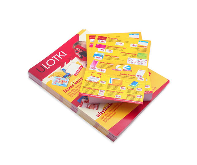 Stos wydrukowanych materiałów reklamowych, w tym arkusze z ofertą cenową i wzorami, ułożony na białym tle pod kątem.