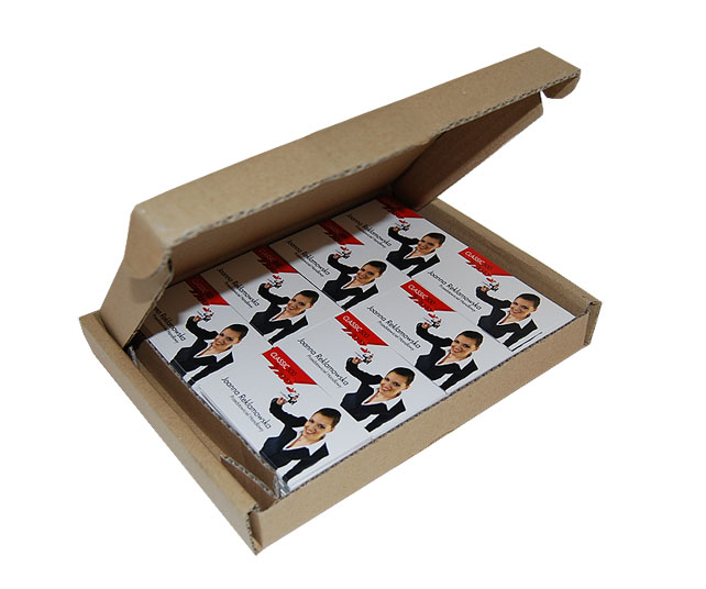 Otwarta kartonowa skrzynka wypełniona rzędami białych kart z portretem kobiety w czarnej marynarce, jej imieniem i nazwiskiem oraz logotypem firmy.