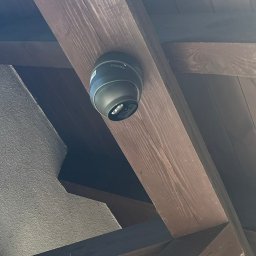INSTA-GUARD'S - Kopułkowa kamera monitoringu marki Pixie zamontowana na drewnianej belce stropowej wewnątrz budynku, widok z dołu.