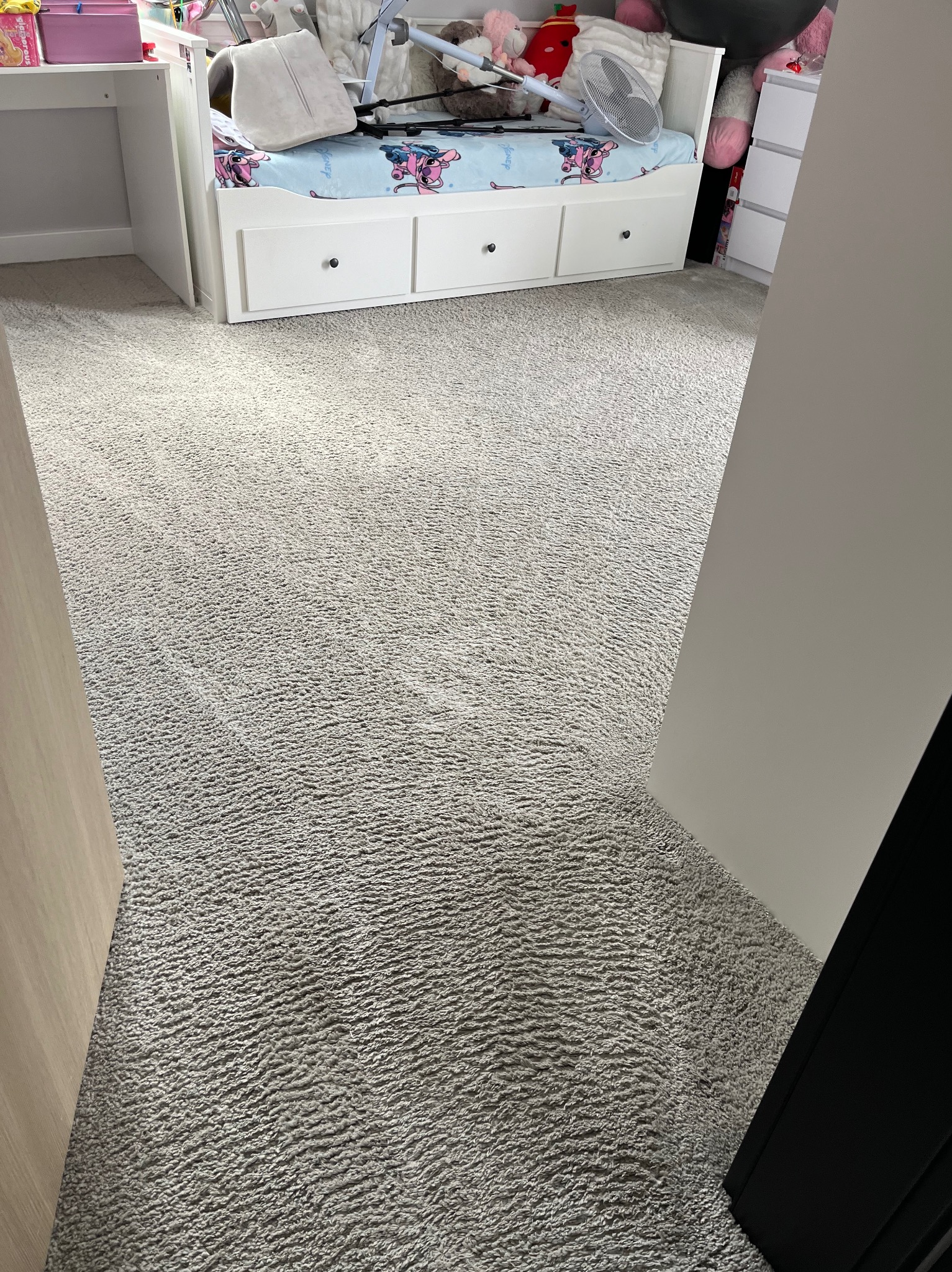 Jasnoszary dywan z krótkim włosiem po profesjonalnym praniu, widoczne ślady odkurzacza, dziecięcy pokój z białymi meblami w tle.