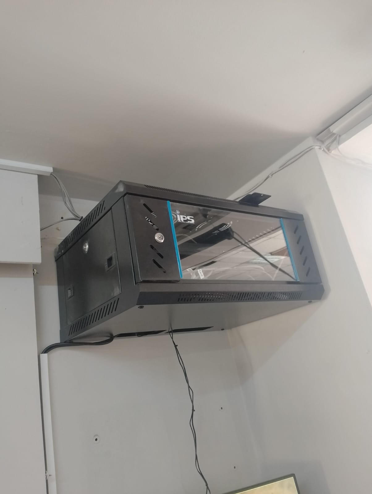 Półka rackowa IPS zamontowana na ścianie, widoczne przewody i elementy instalacji sieciowej.