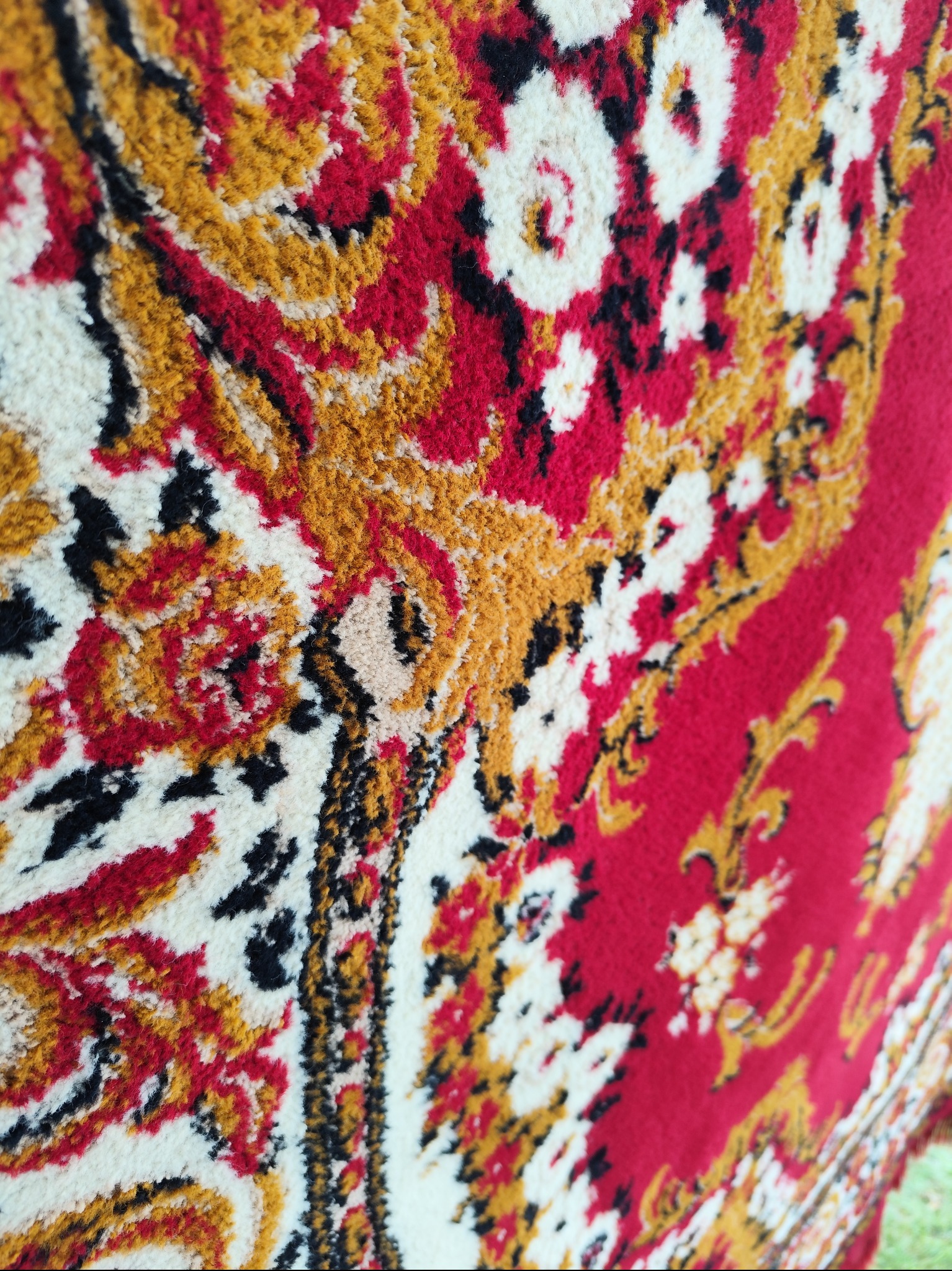 Detale wzoru czerwono-biało-złotego dywanu z bliska, widoczna struktura włókien i orientalny motyw.