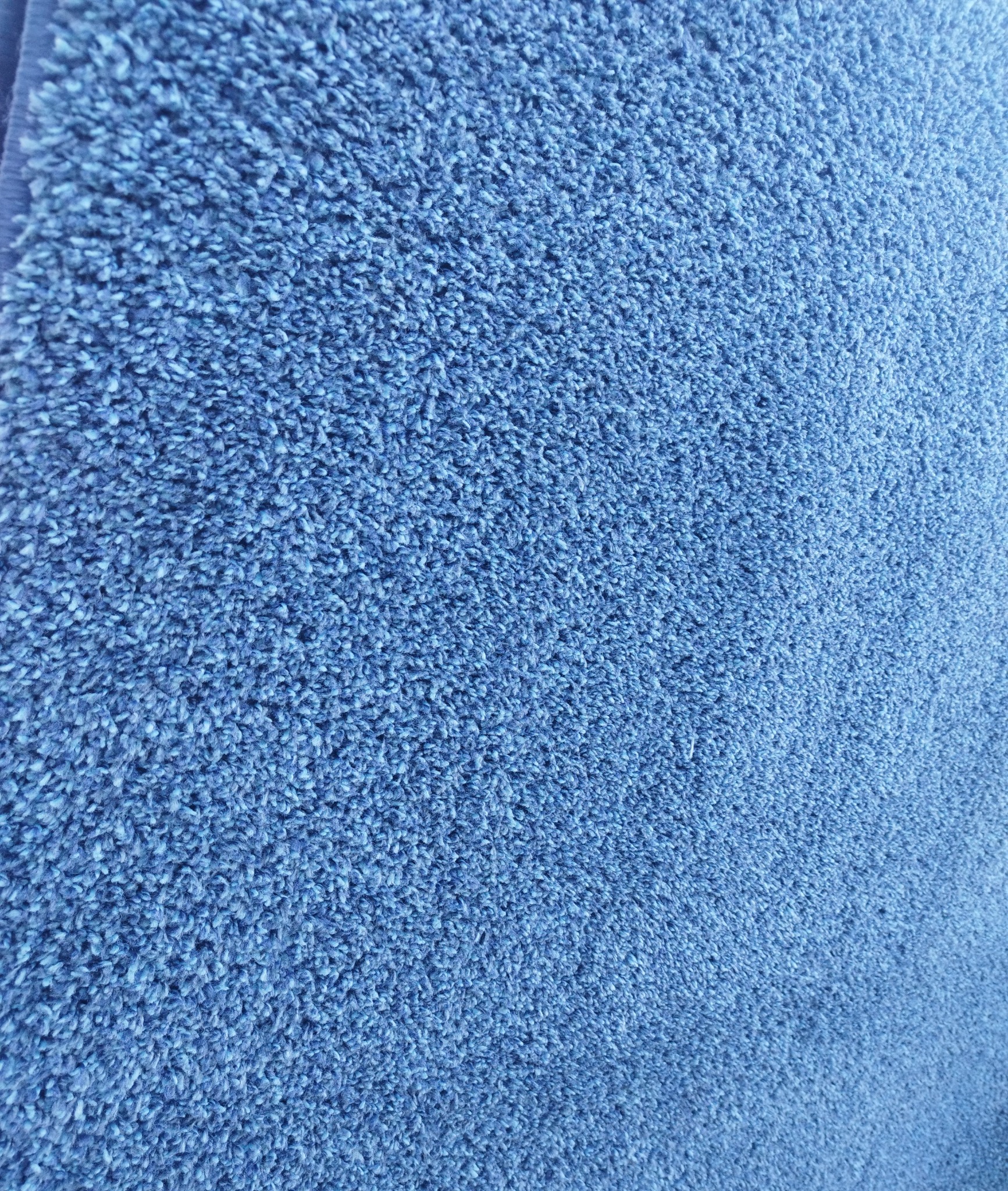 Niebieski dywan z krótkim włosiem, widok z bliska ukazujący strukturę włókien.