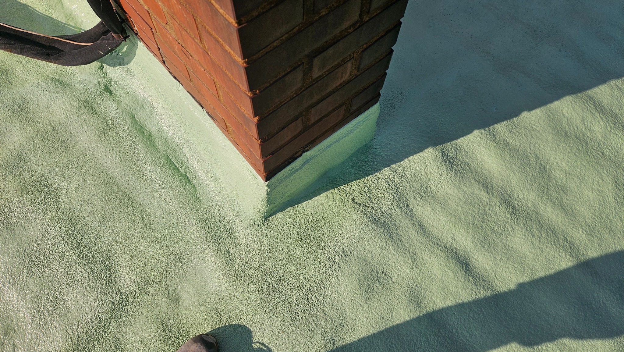 Szczelna izolacja komina pianką w Brennej, widoczna struktura pianki i połączenie z cegłą.