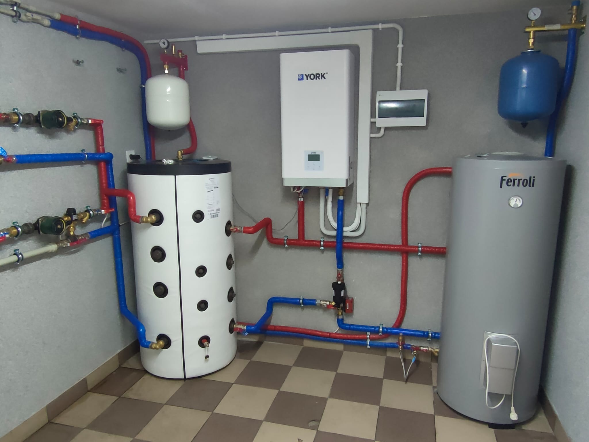 Zakończona instalacja kotłowni w Białymstoku z dwoma zbiornikami, kotłem gazowym York i rozbudowaną siecią rur w kolorach czerwonym i niebieskim.